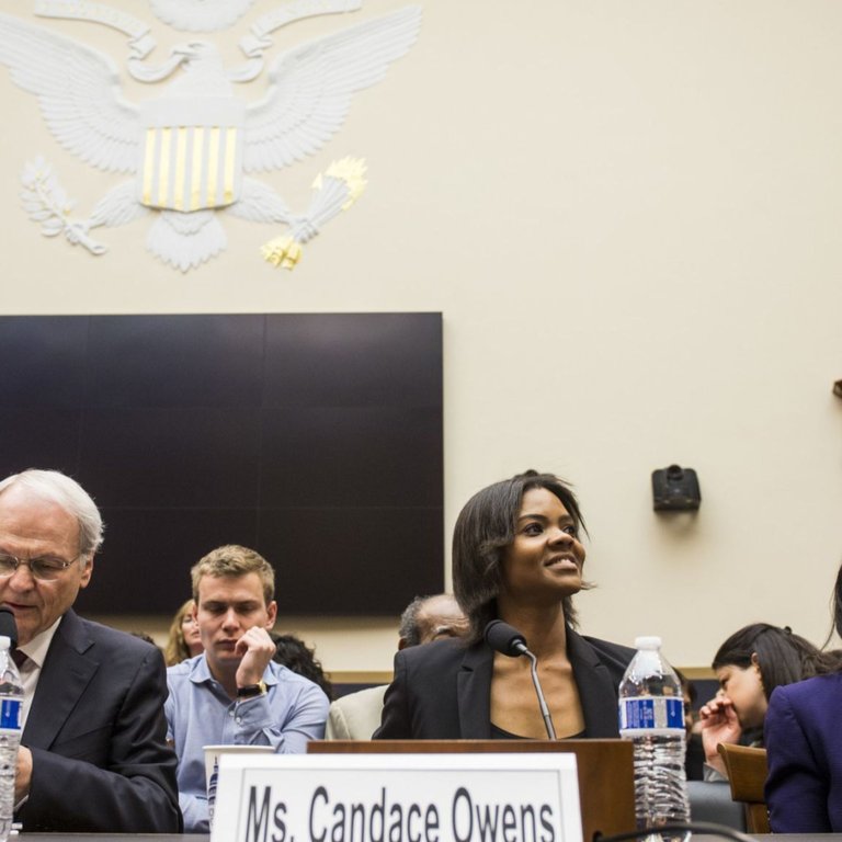 Candace Owens seated at witness table in congressional hearing with nameplate